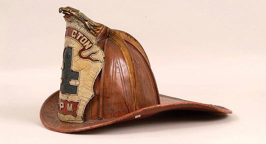 Historic leather firefighter helmet with visible wear and scuffs, representing the long-standing firefighter helmet tradition.