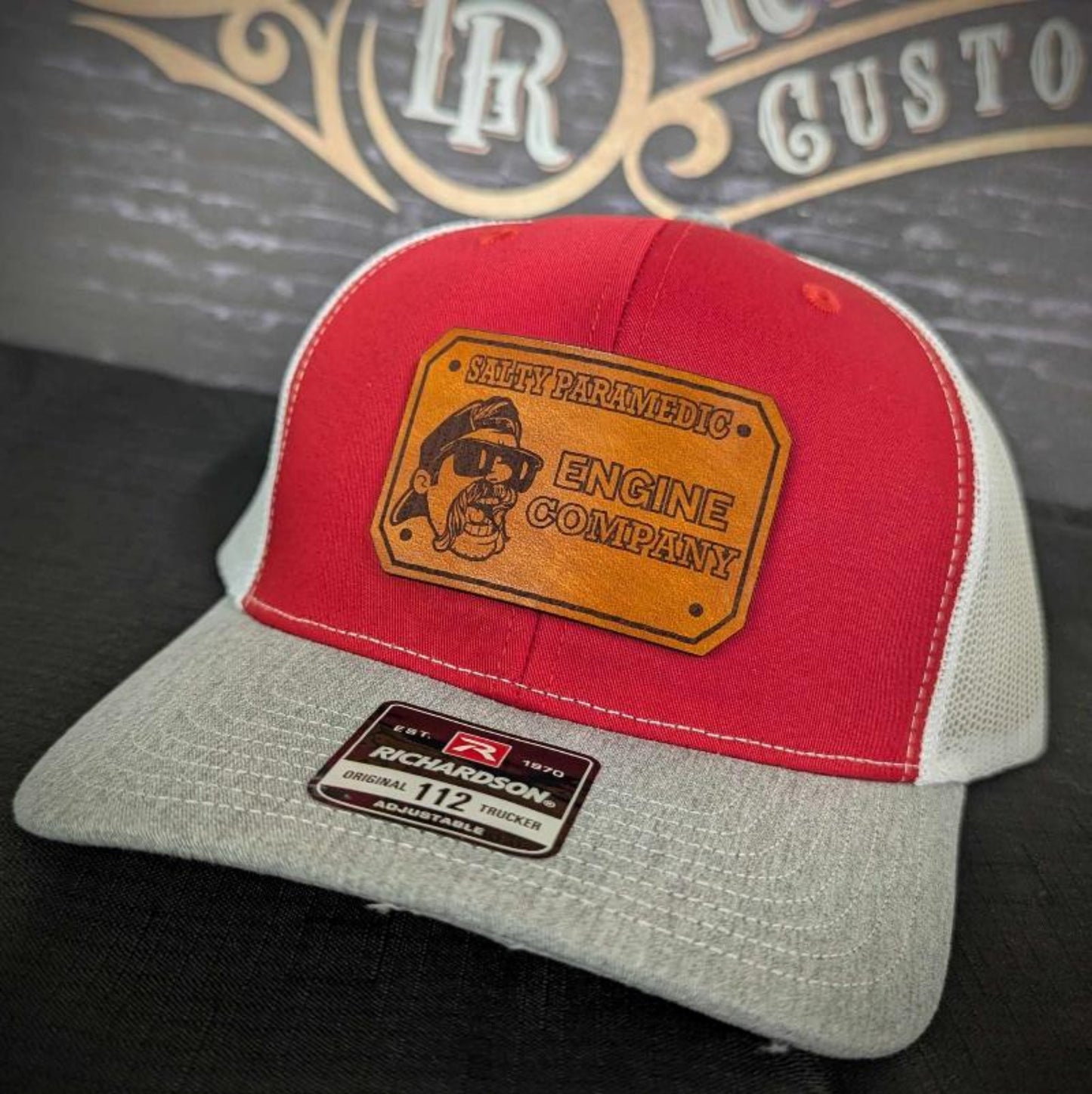 Custom firefighter and EMS hats featuring The Salty Paramedic's leather patch design, shown on Richardson 112 and 110 hats for first responders.