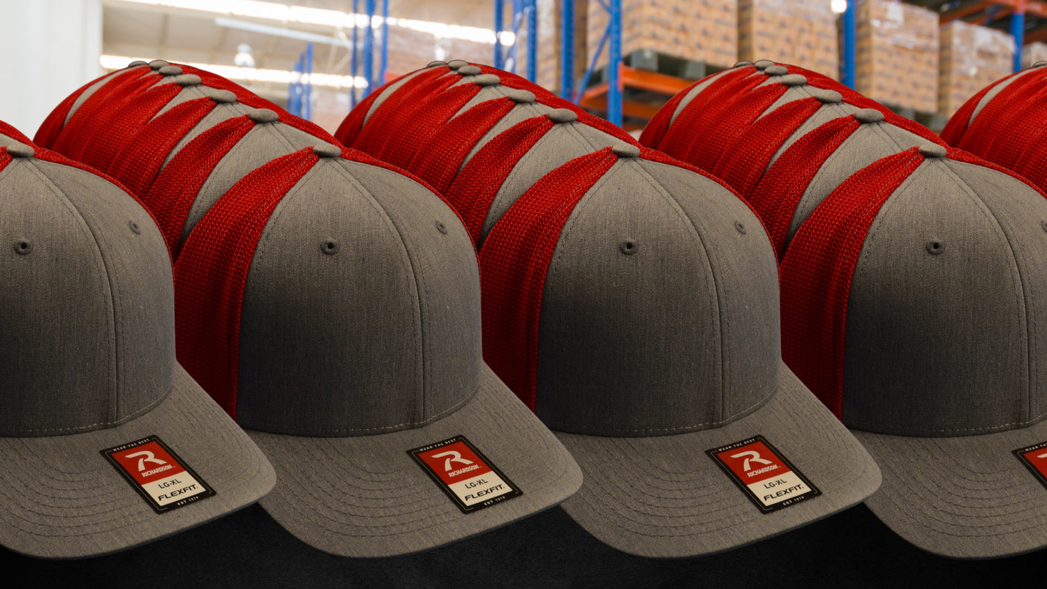 Stack of blank Richardson hats in gray and red mesh ready for bulk orders