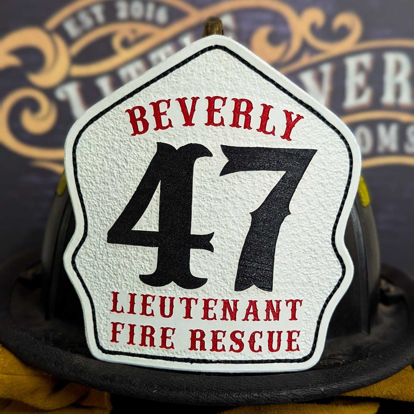 White leather firefighter helmet shield with Beverly lettering, bold black number 47, and lieutenant fire rescue details.