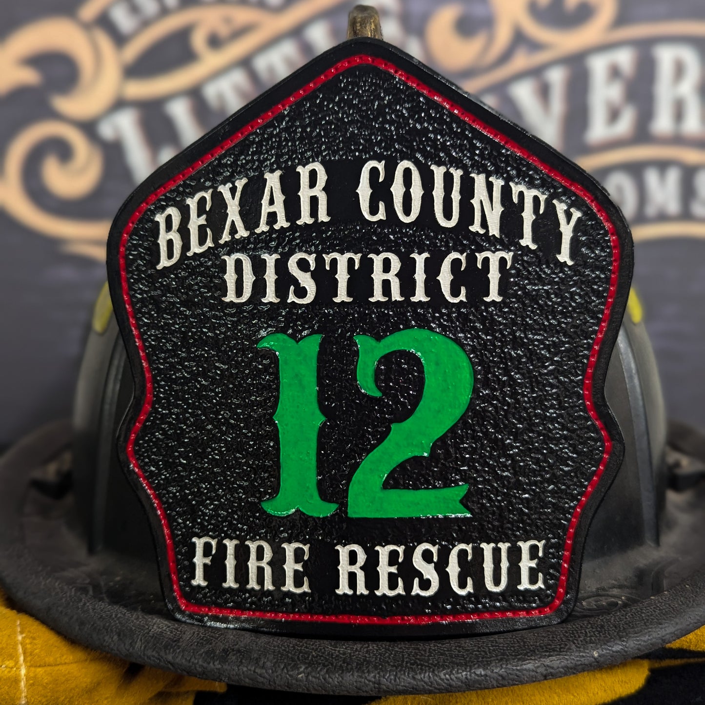 Black leather firefighter helmet shield with Bexar County District lettering, green number 12, and fire rescue details.