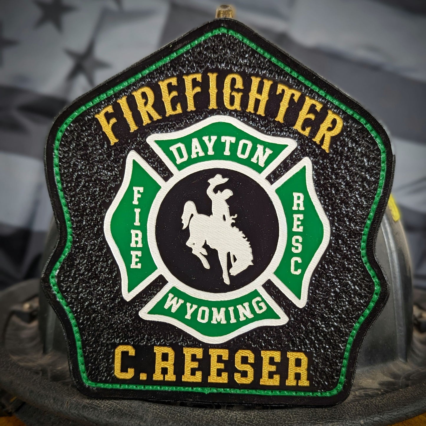 Black leather firefighter helmet shield with green Maltese cross and bucking horse emblem