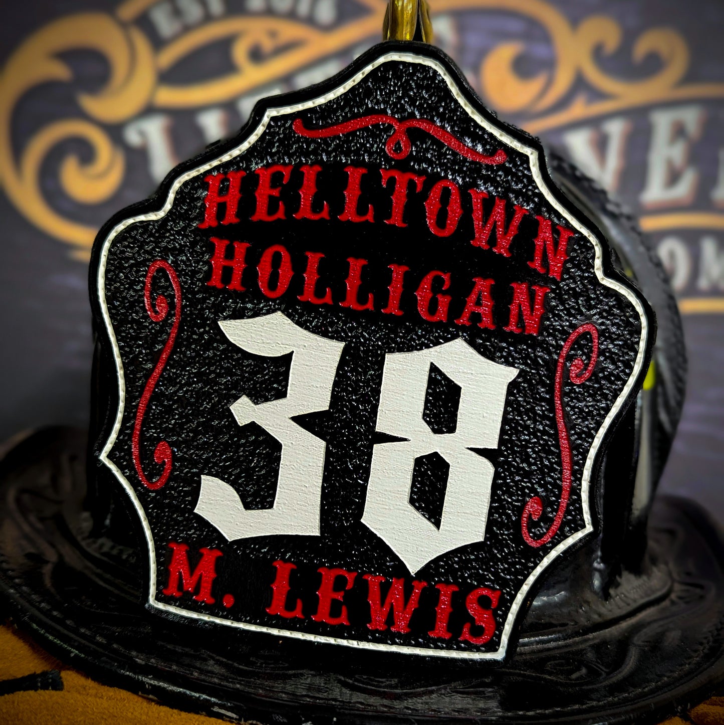 Leather firefighter helmet shield with Helltown Holligan design featuring bold white 38 numbering and red accents.