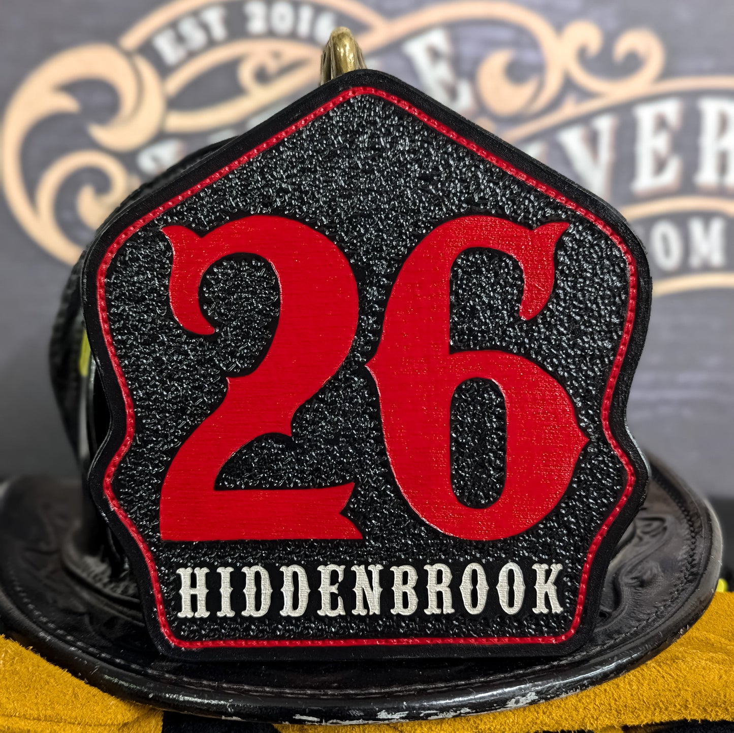 Custom black leather firefighter helmet shield with Hiddenbrook design and large red 26 numbers.