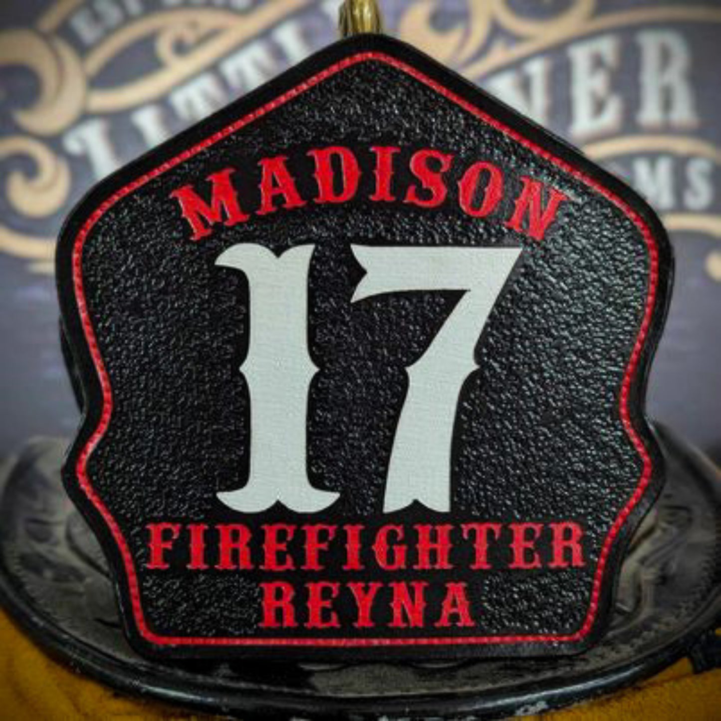 Leather firefighter helmet shield with Madison lettering, bold white number 17, and firefighter Reyna name.