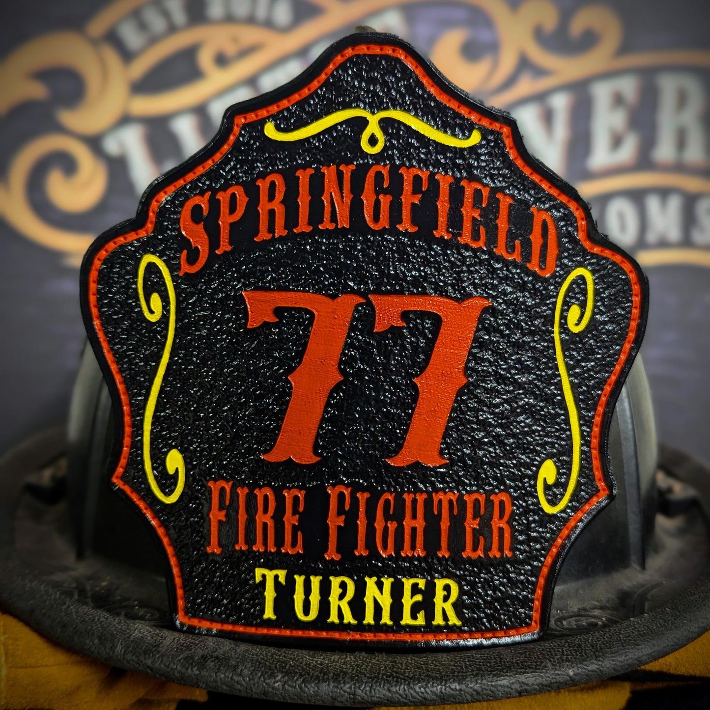 Black leather firefighter helmet shield with Springfield lettering, bold orange number 77, and firefighter Turner name.