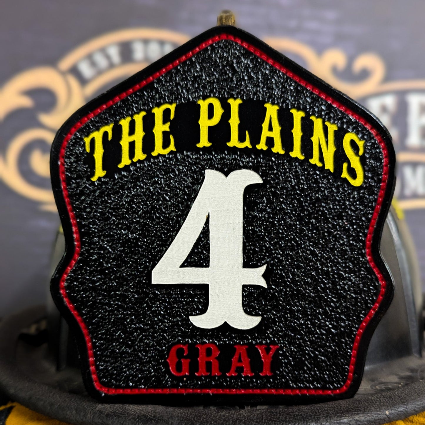 Custom leather firefighter helmet shield with The Plains design and bold white number 4.