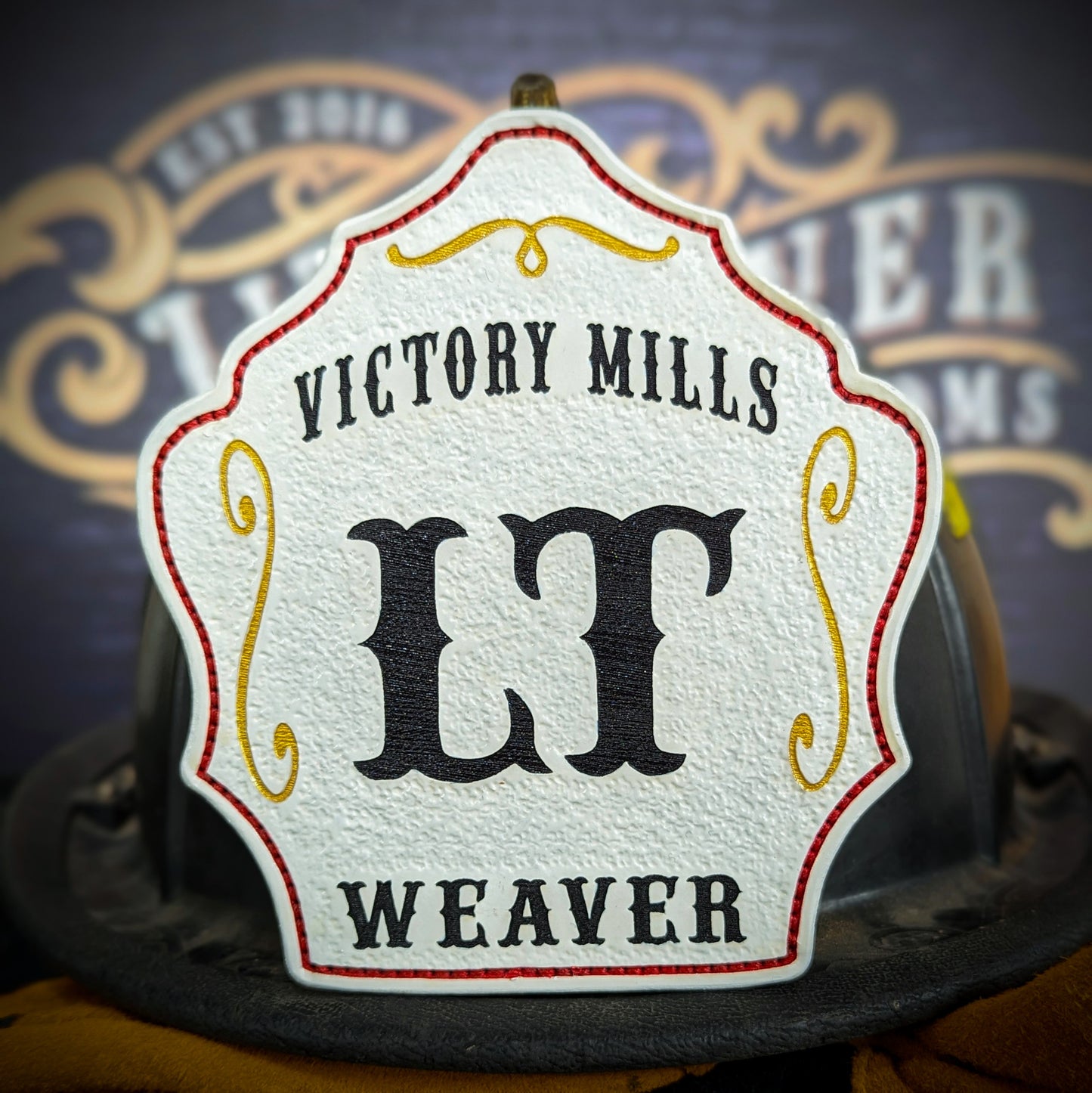 White leather firefighter helmet shield with Victory Mills lettering, bold black LT rank, and Weaver name.