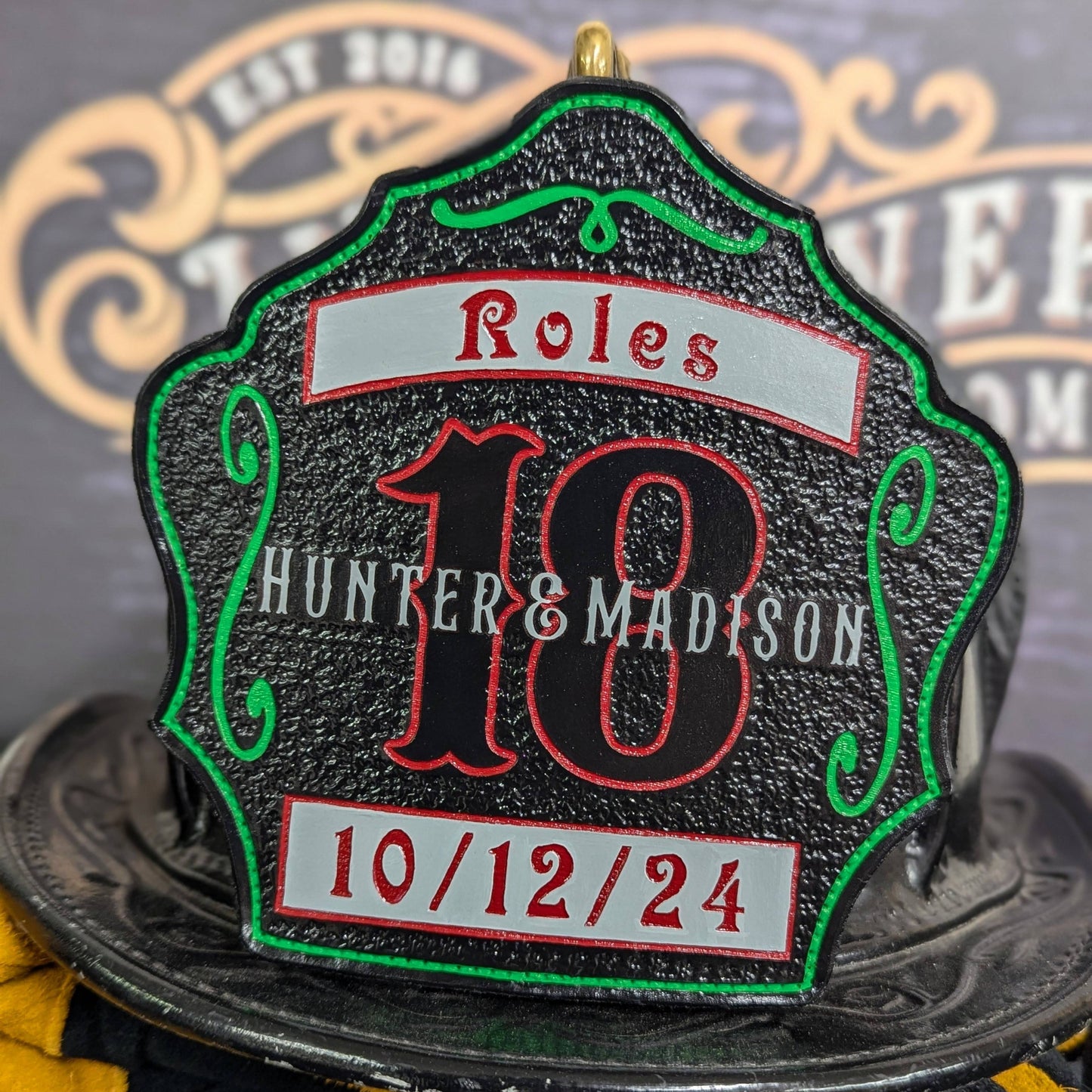 Green medallion leather firefighter helmet shield with banner/date detail on black