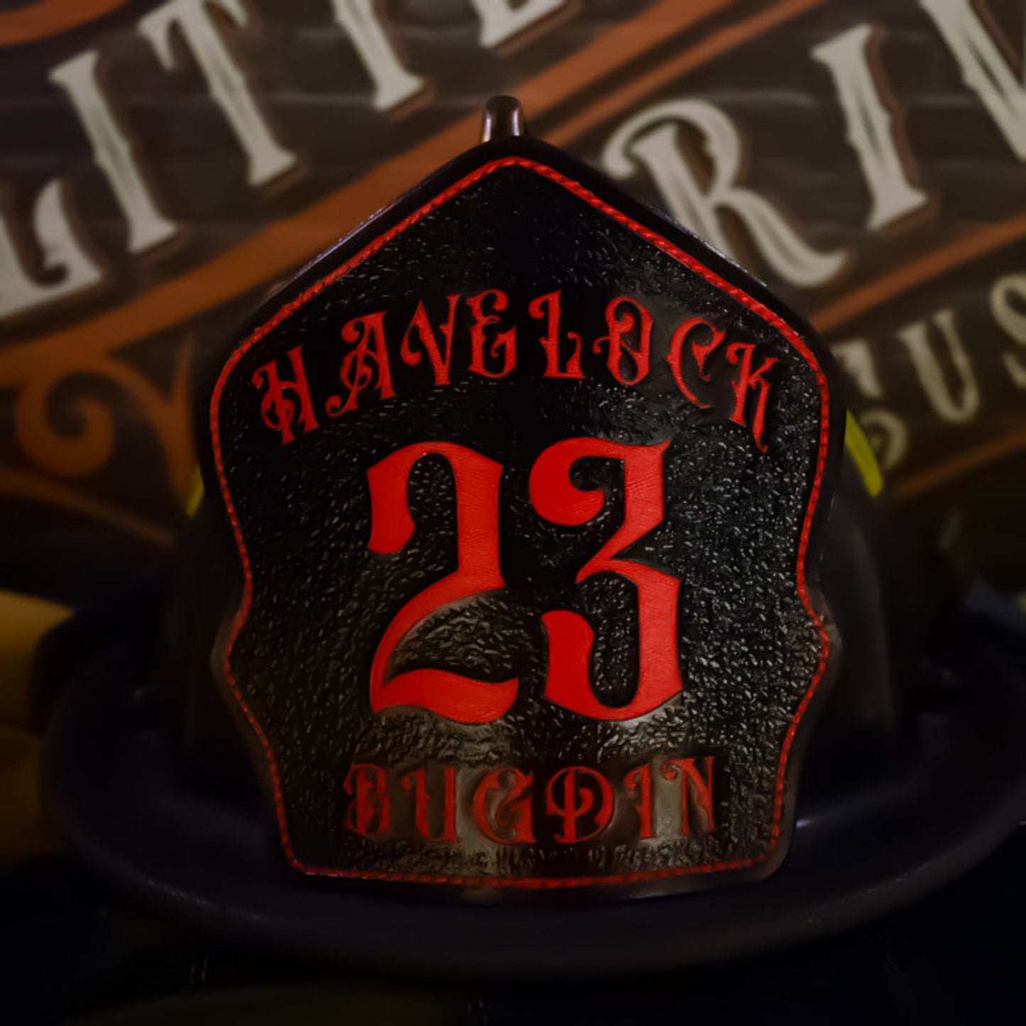avelock firefighter helmet shield with bold red 23 and Bugdin text on black leather background.