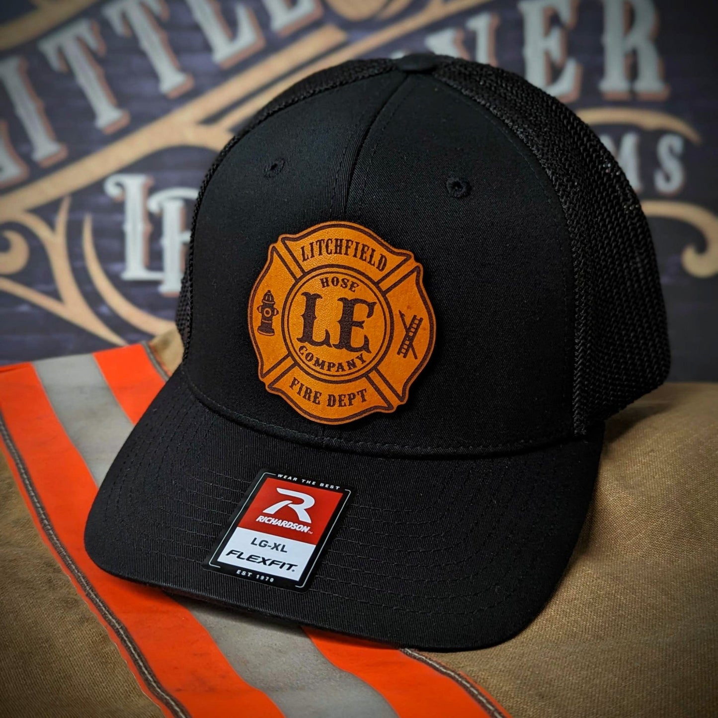 Black Richardson firefighter hat with custom Maltese leather patch design, Flexfit style built for fire department crews.