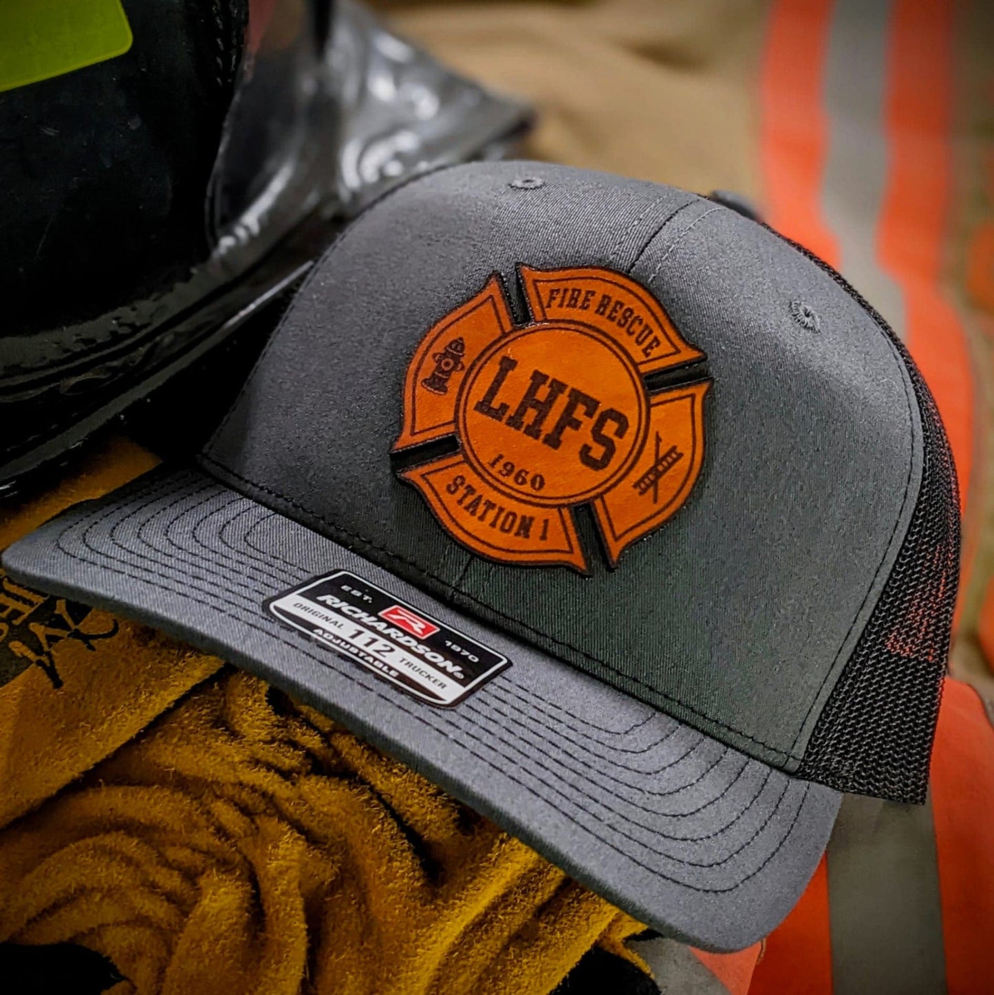 Dark gray Richardson firefighter hat with custom Maltese leather patch design, durable gear for fire rescue crews.