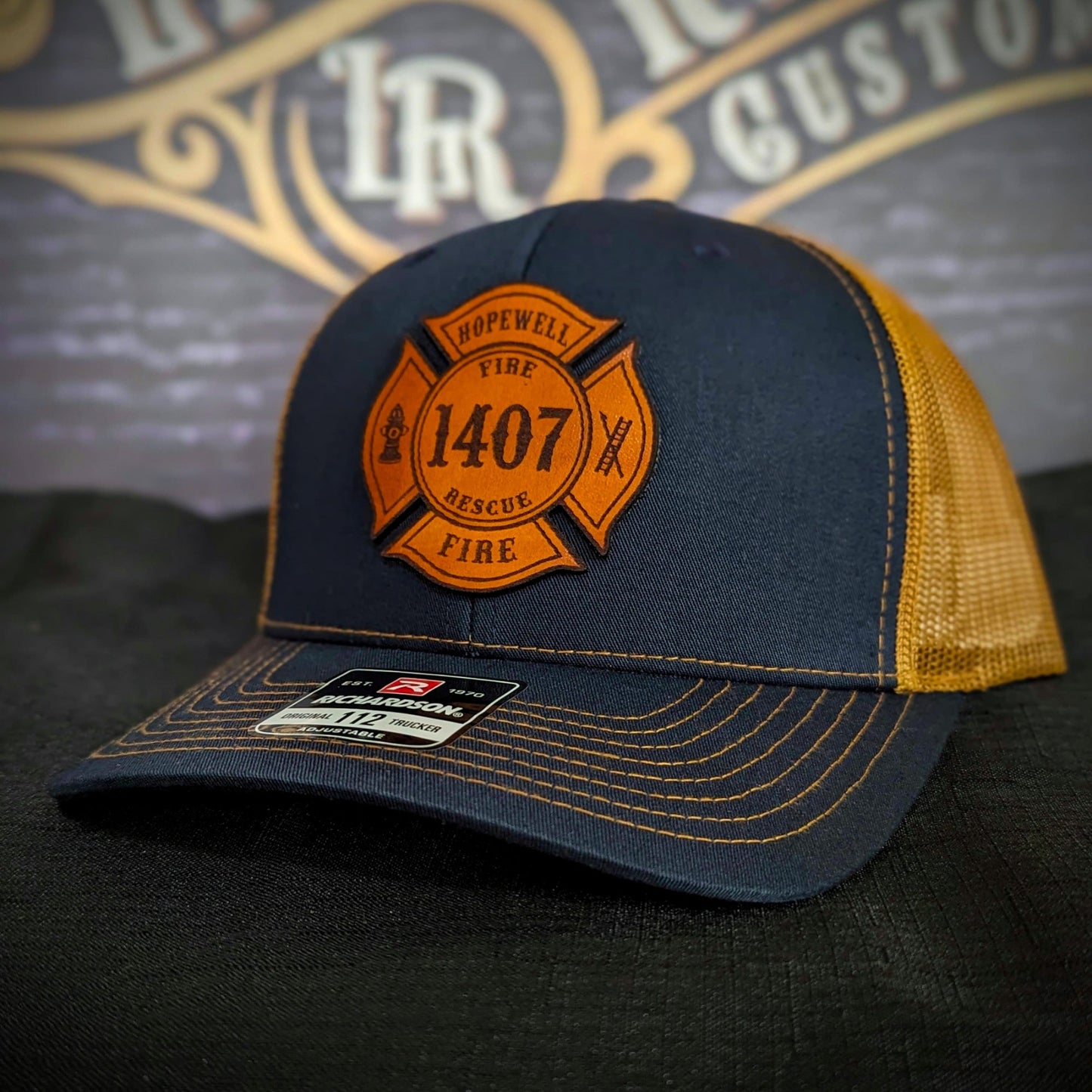 Navy Richardson firefighter hat with custom Maltese leather patch design and gold mesh back, rugged gear for fire rescue crews.