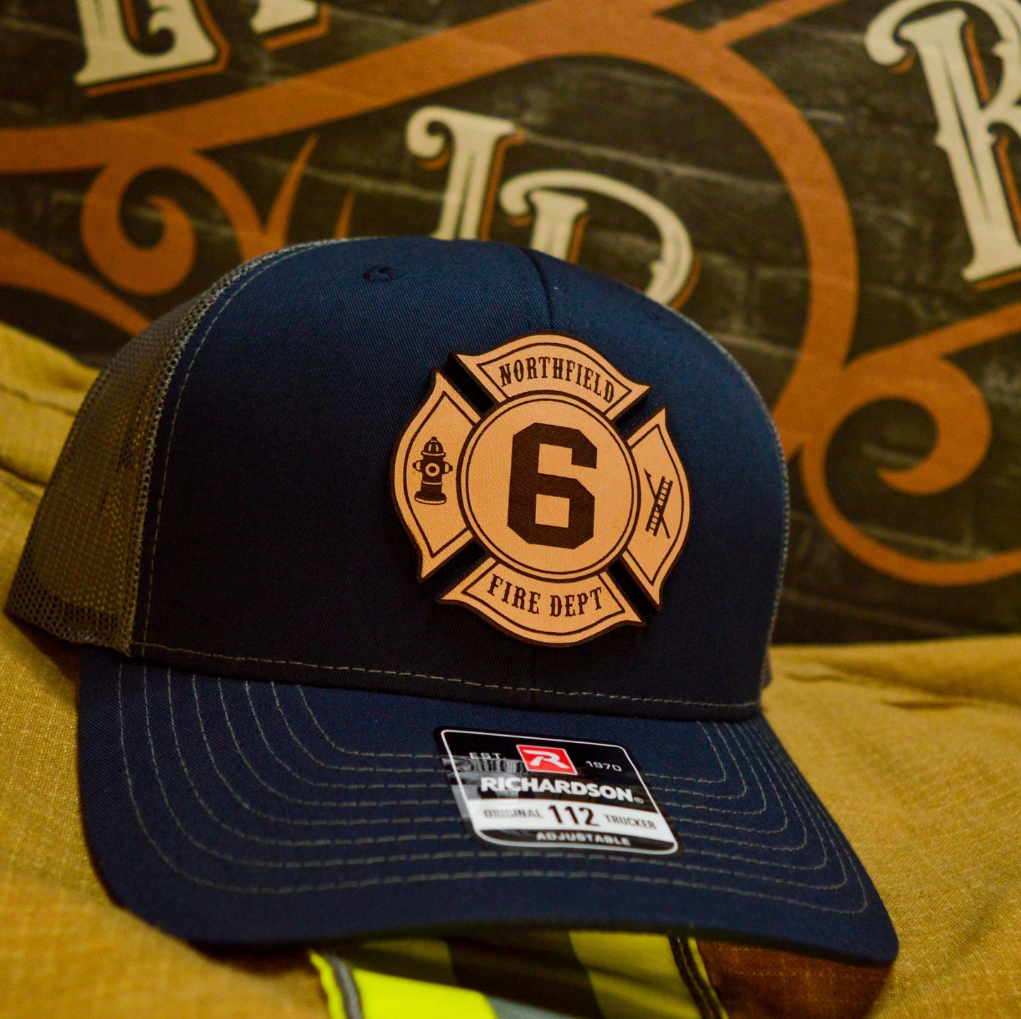 Navy and gray Richardson firefighter hat with custom Maltese leather patch design, durable headwear for fire department crews.