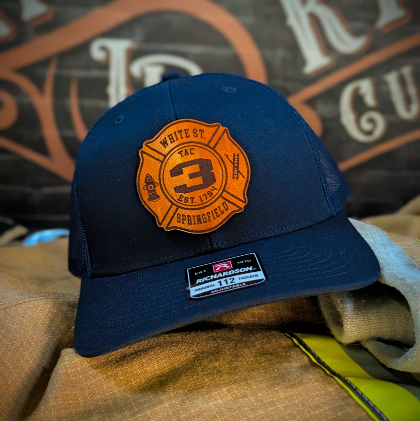 Navy Richardson firefighter hat with custom Maltese leather patch design, classic headwear for fire service professionals.