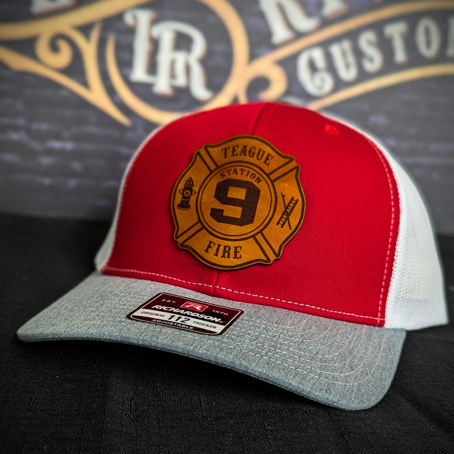 Red and gray Richardson firefighter hat with custom Maltese leather patch design, bold and durable fire station headwear.