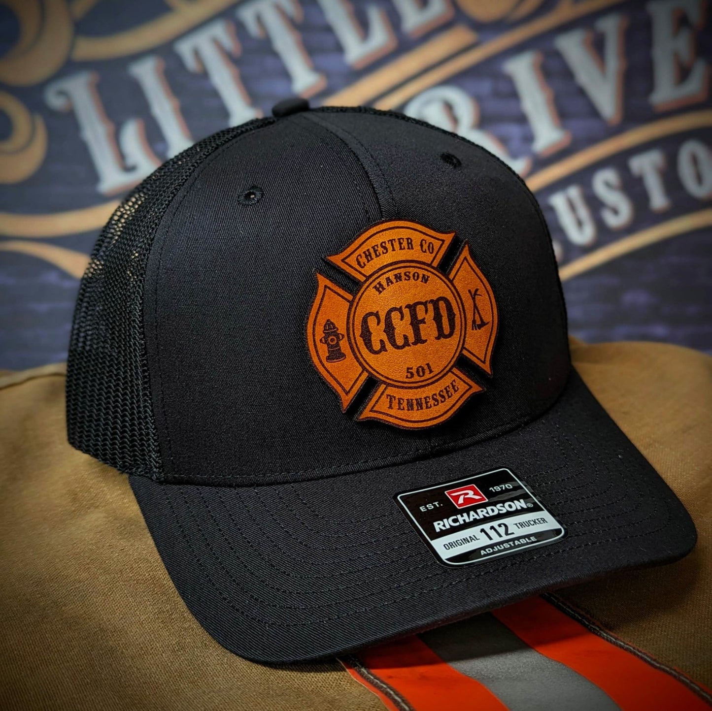 Black Richardson firefighter hat with custom Maltese leather patch design, durable mesh back style for fire department crews.