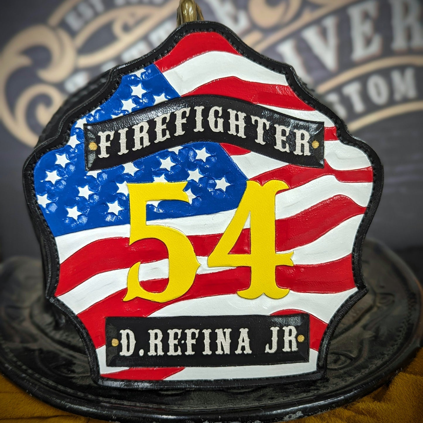 Custom firefighter helmet shield with American flag design, personalized leather front with unit number and firefighter name. Handcrafted fire helmet shield for professional firefighters, made for durability and pride on the job.