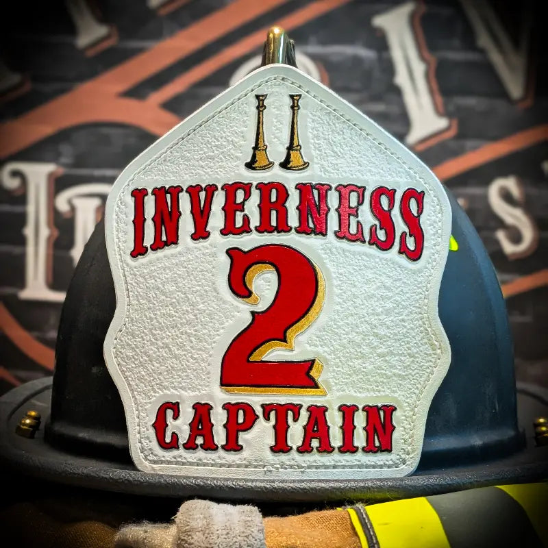 Custom leather firefighter helmet shield featuring Inverness Captain 2 design with gold bugles