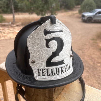 Custom firefighter helmet shield for Telluride Co. 2 – black and white leather with bold lettering, handcrafted by Little River Customs.
