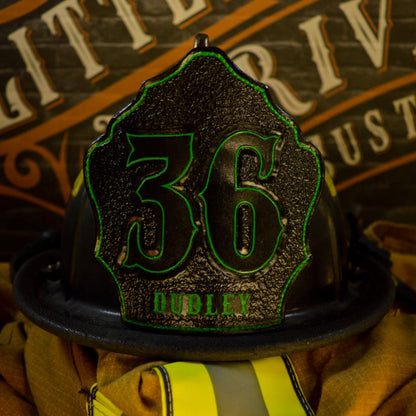 Black leather firefighter helmet shield with large “36” and neon-green outline, “DUDLEY” name at the base—mounted on a helmet.
