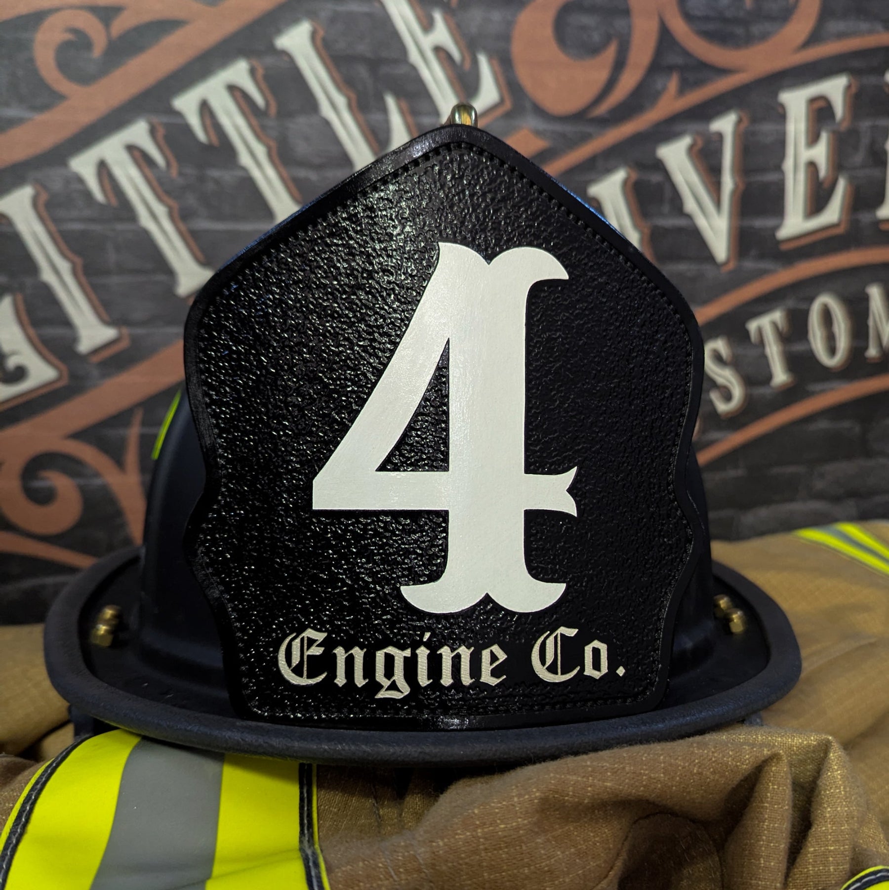 Black leather firefighter helmet shield with large white numeral “4” and “Engine Co.” lettering—mounted on a helmet.