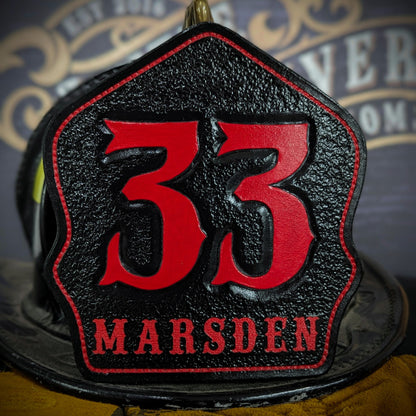 Black leather firefighter helmet shield with oversized red numerals “33,” red border outline, and “MARSDEN” name lettering—mounted on a helmet.