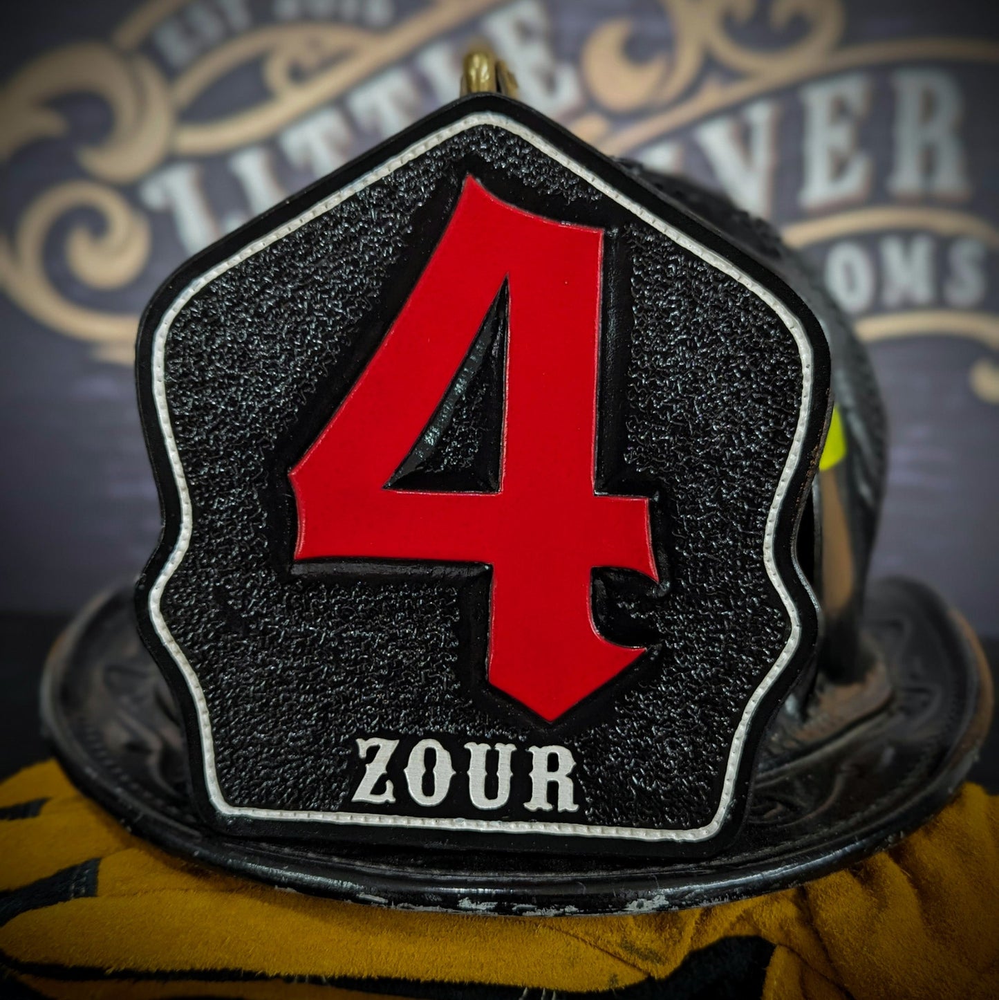 Black leather firefighter helmet shield with oversized red numeral “4” and white name lettering—mounted on a helmet.