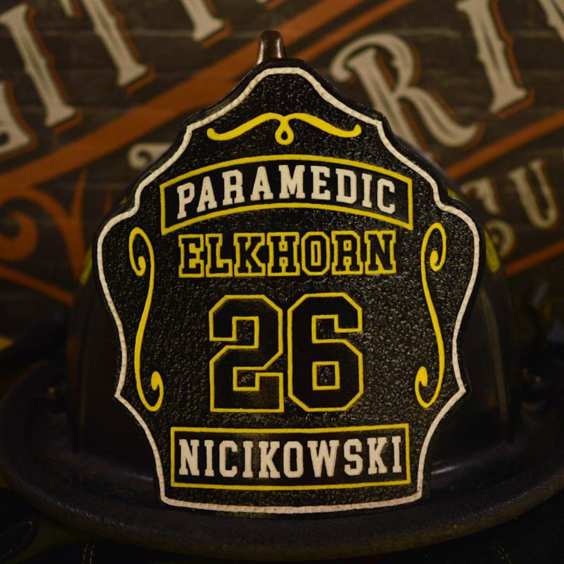 Black leather firefighter helmet shield with yellow paramedic block panel and fine border.