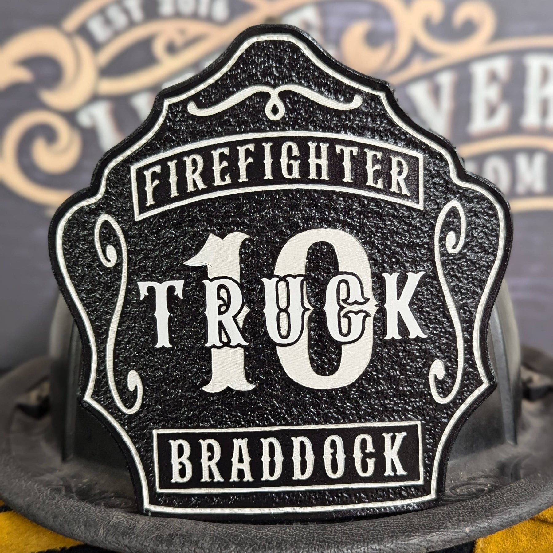 Charcoal truck leather firefighter helmet shield with bold white lettering, textured finish.