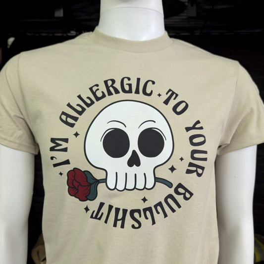 Beige t-shirt with cartoon skull graphic holding a rose and bold “I’m Allergic to Your Bullsh*t” text – sarcastic humor shirt with attitude