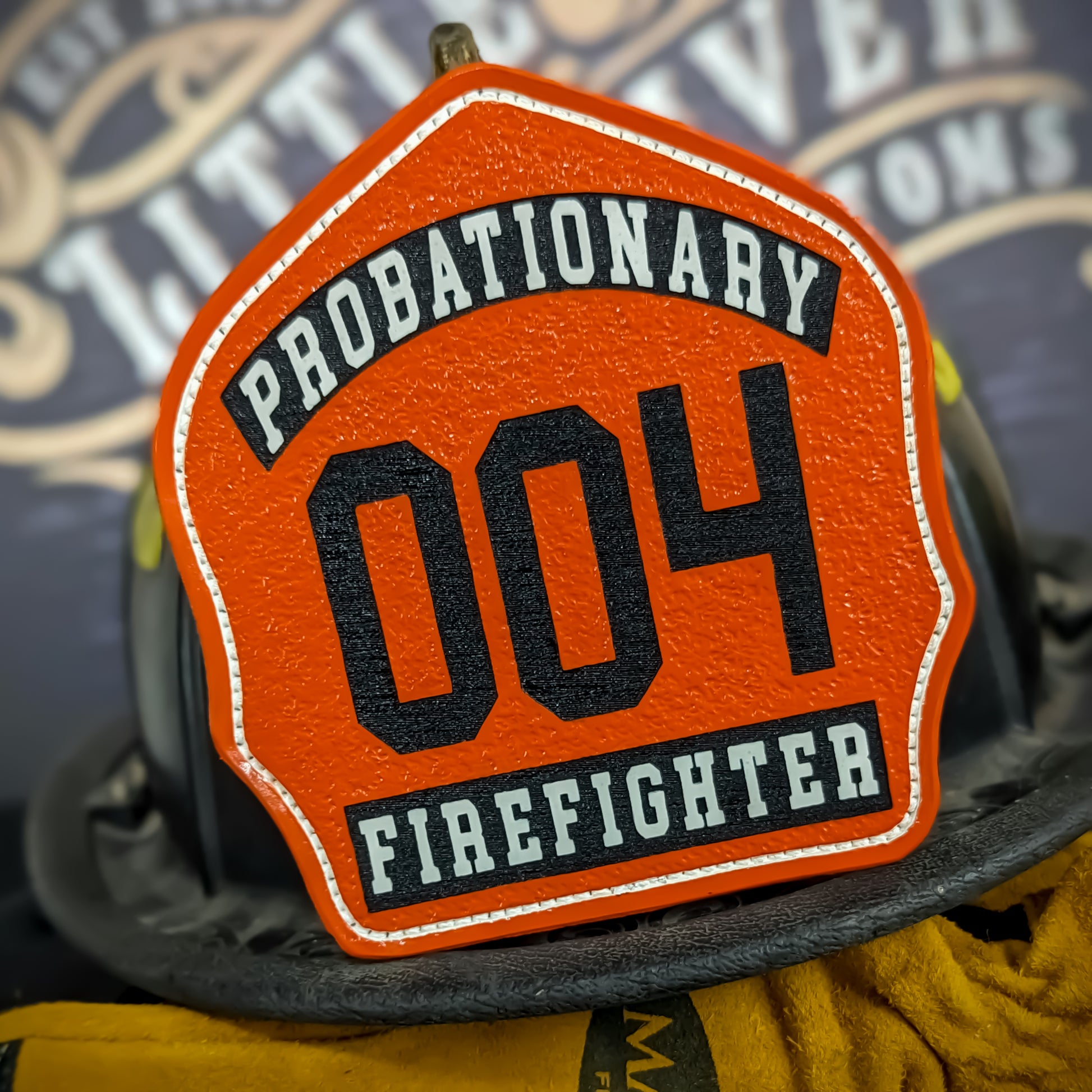 Bright orange leather firefighter helmet shield with large black number 004, top banner reading Probationary, bottom banner Firefighter, designed for new recruits.