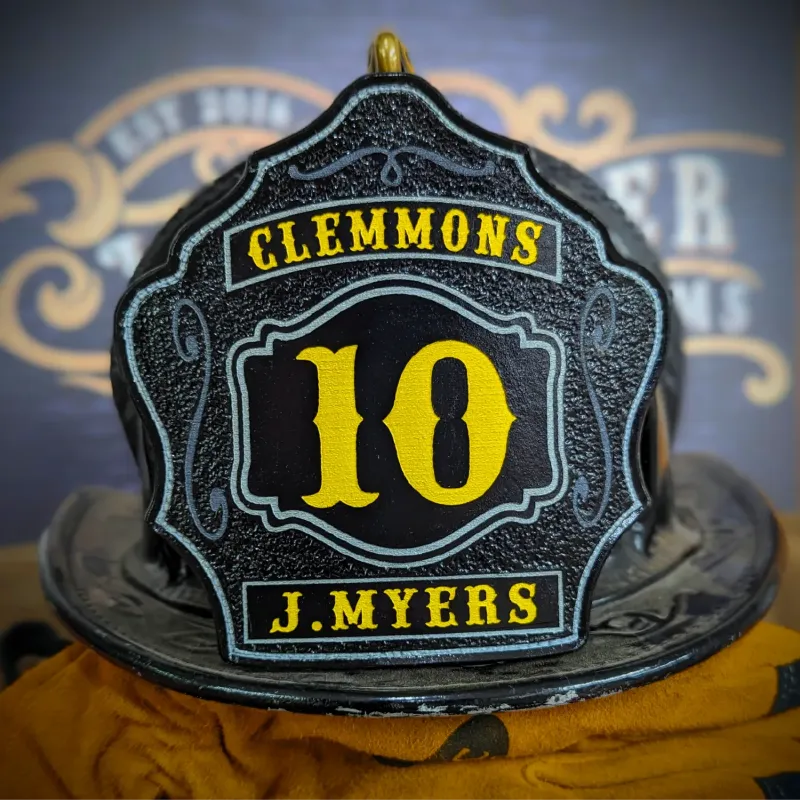 Custom firefighter helmet shield with number 10, Clemmons lettering, and J. Myers name in black leather with bold yellow details.
