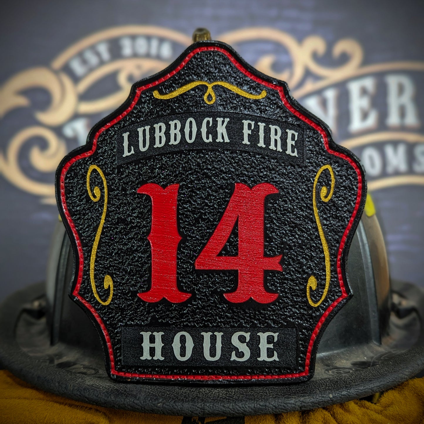 Custom black leather firefighter helmet shield with large red number 14, gray Lubbock Fire text at top, and House nameplate at bottom.