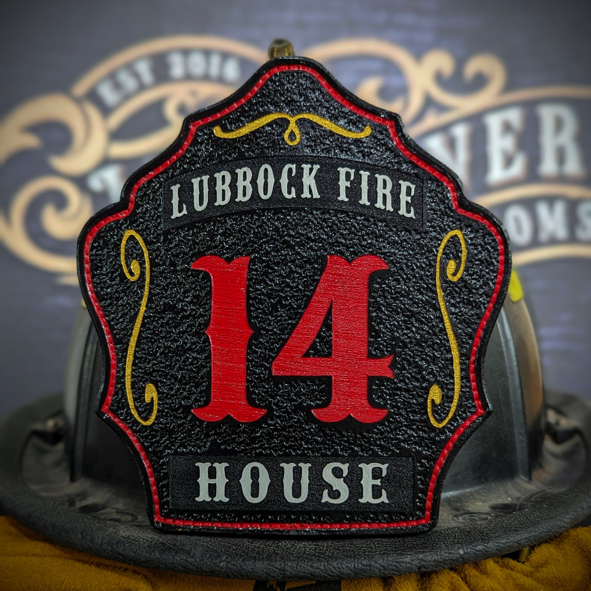 Custom black leather firefighter helmet shield with large red number 14, gray Lubbock Fire text at top, and House nameplate at bottom.