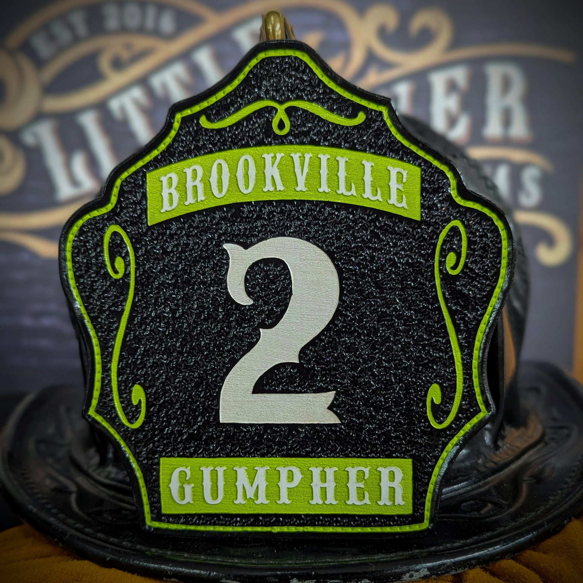 Black leather firefighter helmet shield with white number 2, green Brookville text, and name Gumpher.
