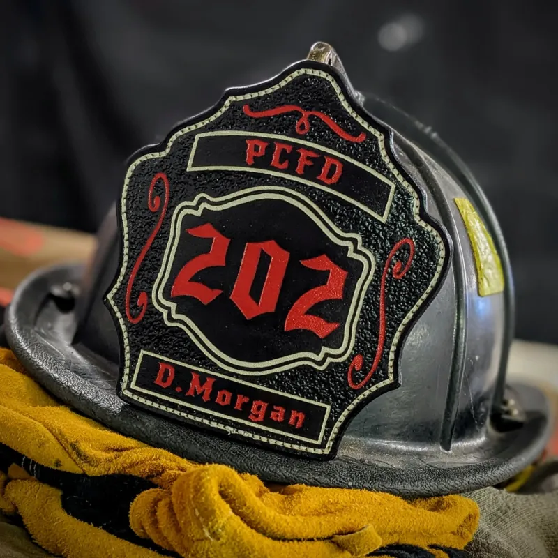 Black leather firefighter helmet shield with bold red number 202, PCFD banner at the top, D. Morgan nameplate at the bottom, and decorative red scroll accents.