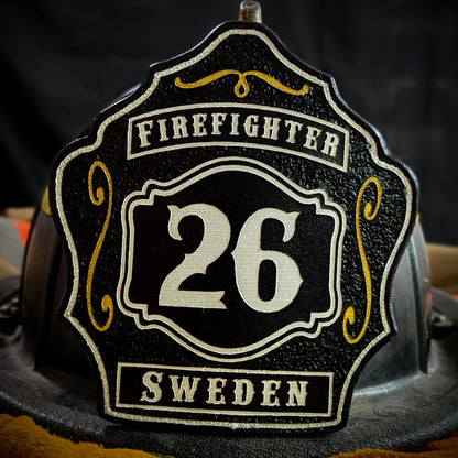 Custom black leather firefighter helmet shield with number 26 in white, gold scroll accents, and bold firefighter text