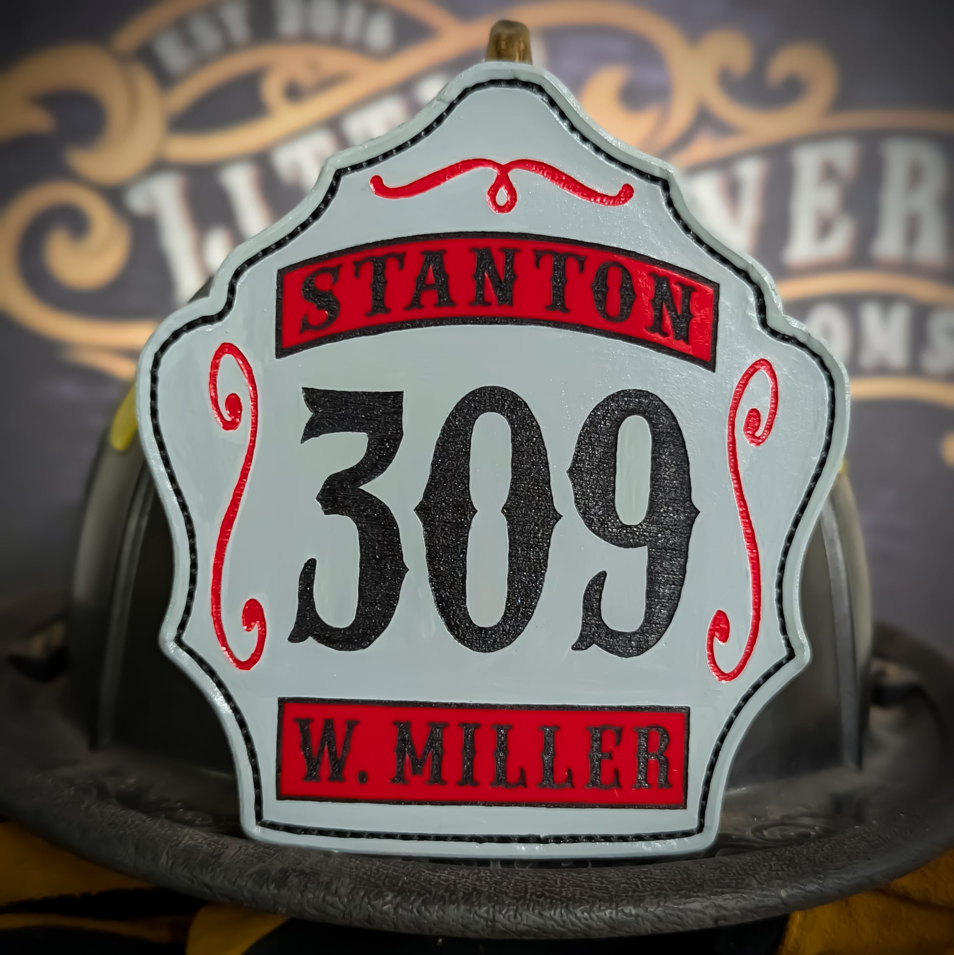 Custom white leather firefighter helmet shield with number 309, red banners, black lettering, and decorative scroll accents