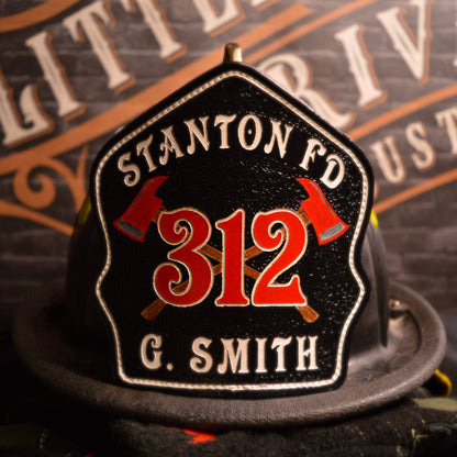 Black leather firefighter helmet shield with crossed red axes and bold red number 312, custom fire department gear.