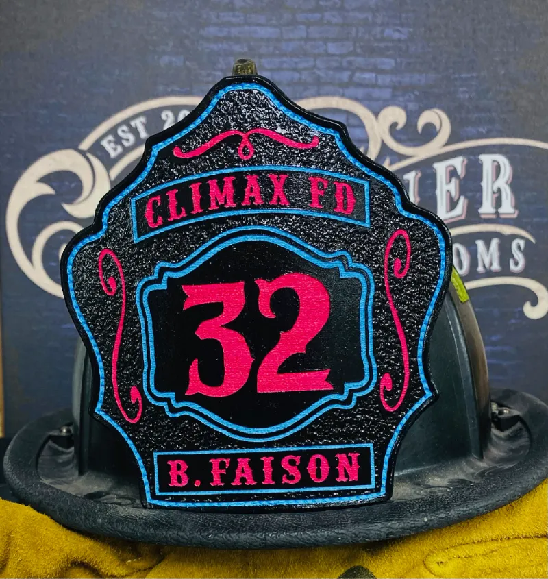 Custom firefighter helmet shield with number 32, Climax FD lettering, and B. Faison name in black leather with bold pink and blue details.