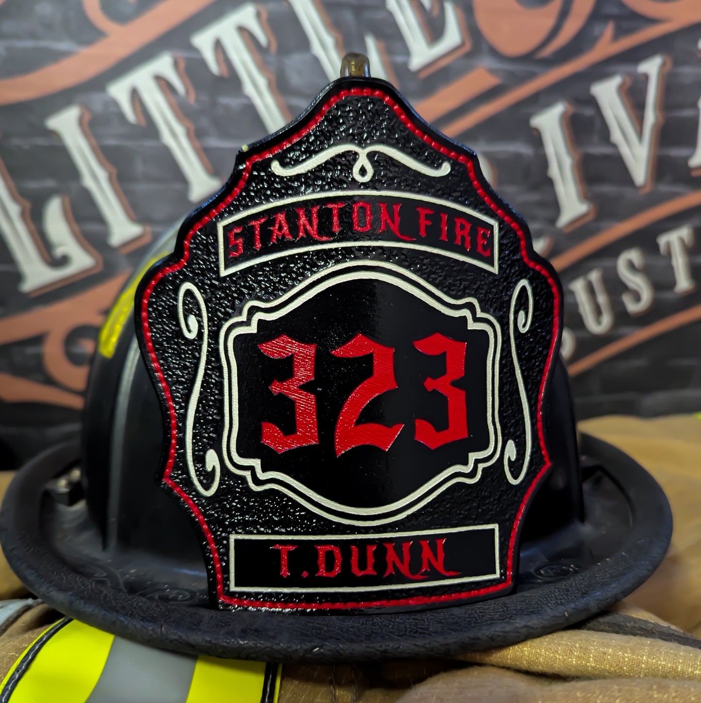 Black leather firefighter helmet shield with red 323 numbers, Stanton Fire text, and name T. Dunn.