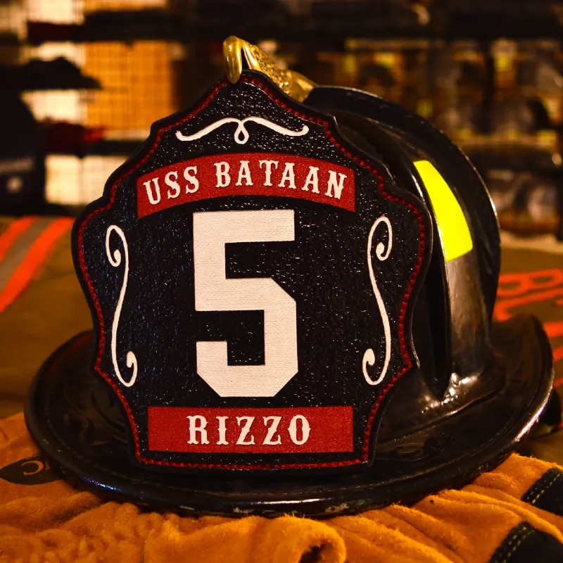 Custom black leather firefighter helmet shield with large white number 5, USS Bataan banner at the top, Rizzo nameplate at the bottom, and red decorative accents.