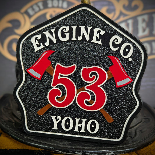 Black leather firefighter helmet shield with crossed red axes and bold red number 53, custom fire department gear.