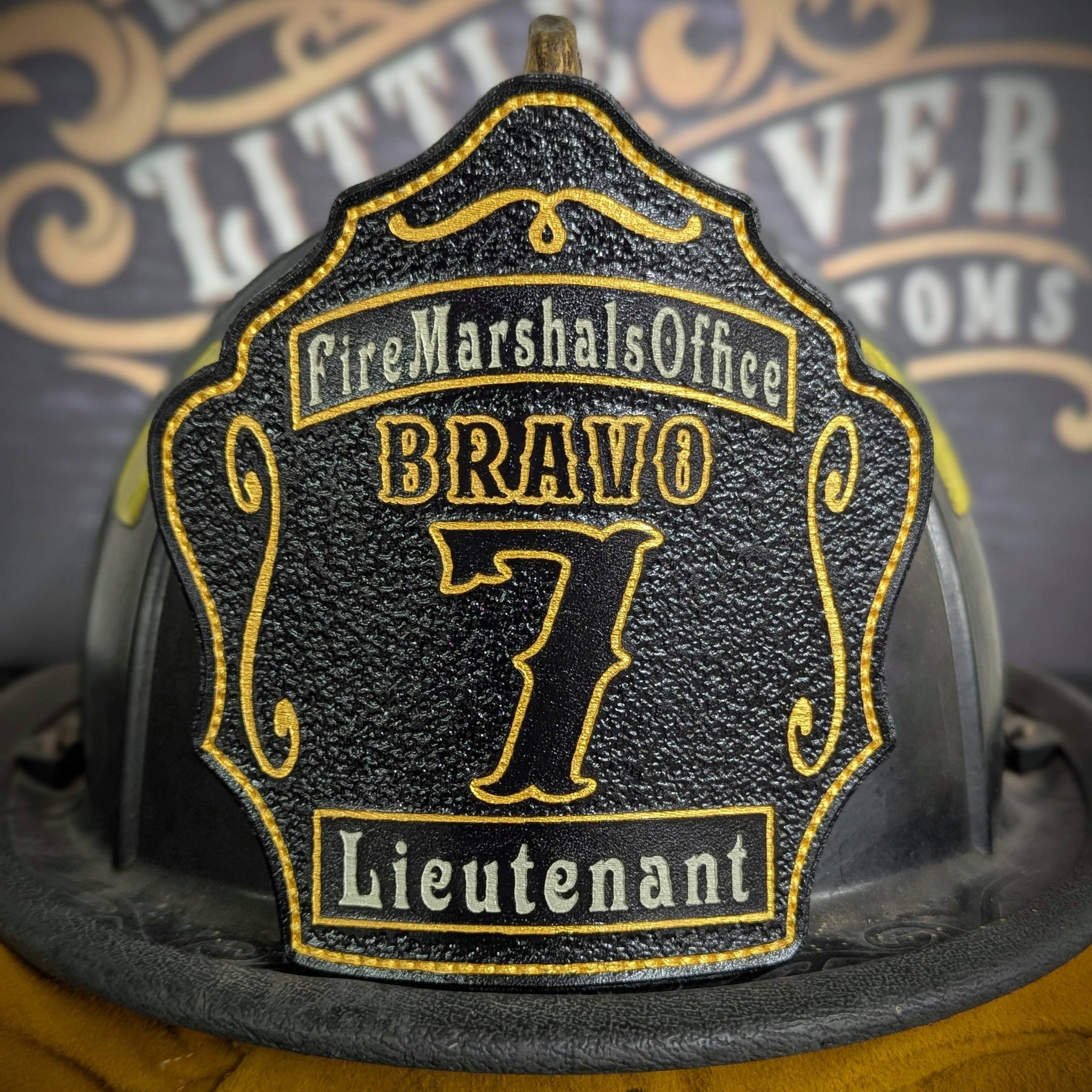 Black leather firefighter helmet shield with bold yellow number 7 and fire marshal lettering, custom fire department gear.