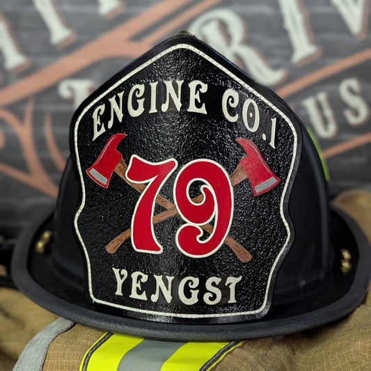 Black leather firefighter helmet shield with crossed red axes and bold red number 79, custom fire department gear.