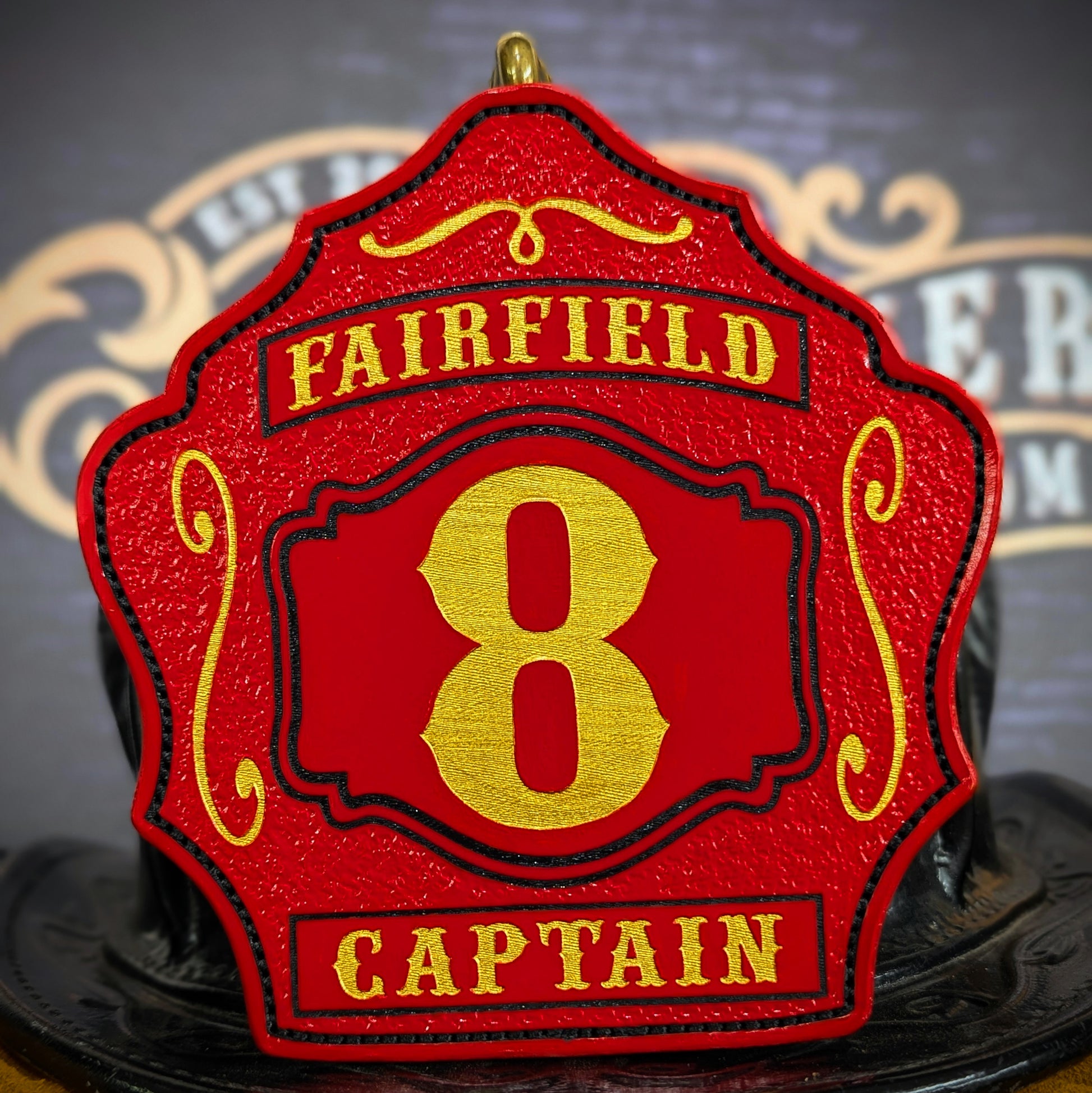 Red leather firefighter helmet shield with bold gold number 8, Fairfield text above, and Captain title at the bottom.
