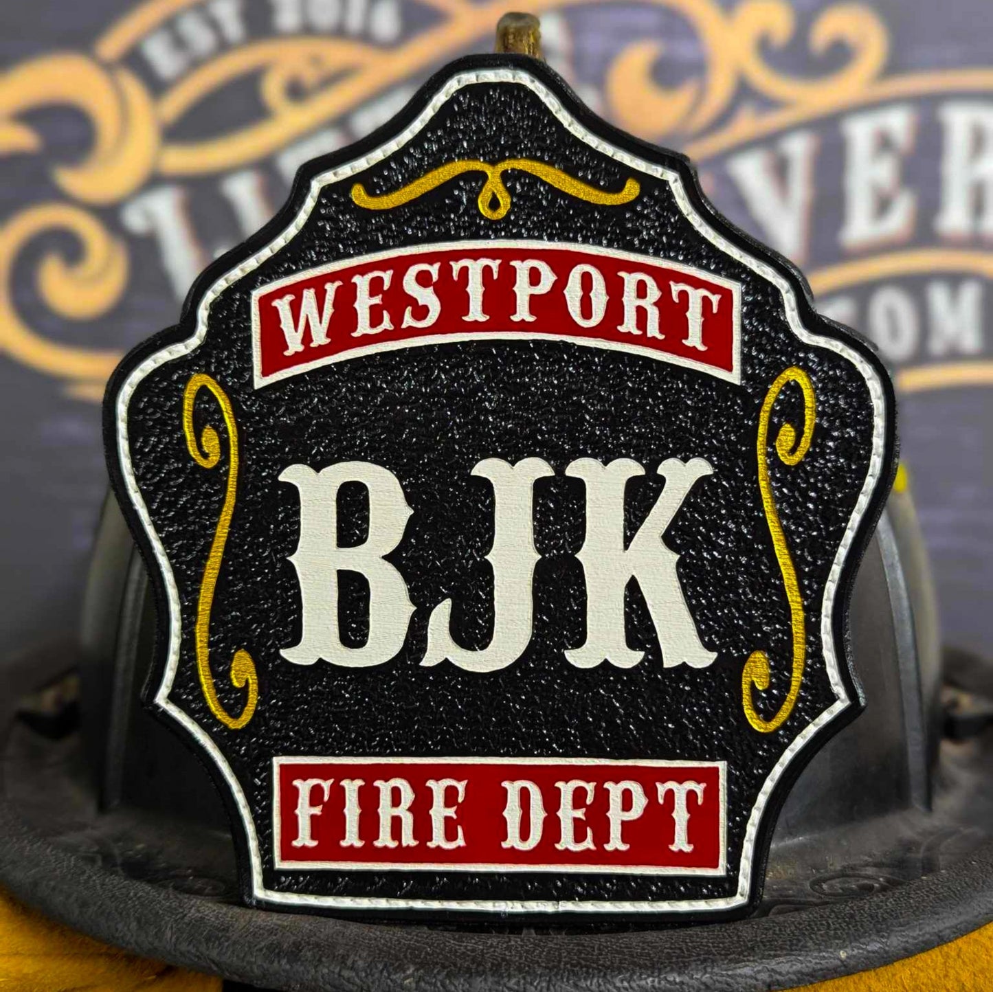 Black leather firefighter helmet shield with white BJK letters, red Westport and Fire Dept text, and yellow decorative details.