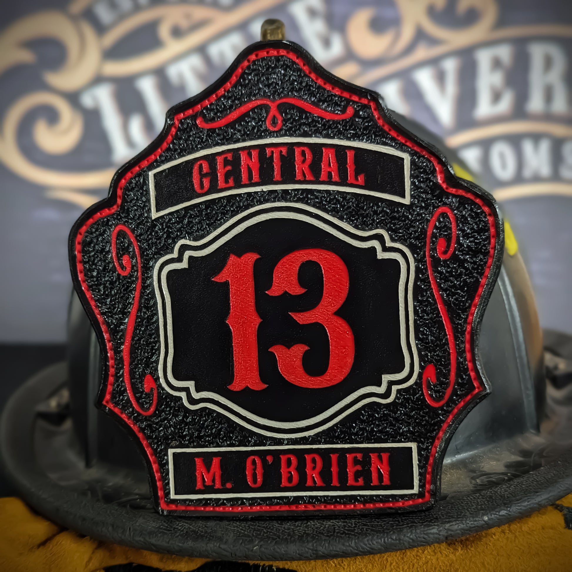 Black leather firefighter helmet shield with red number 13, Central text above, and name M. O’Brien at the bottom.