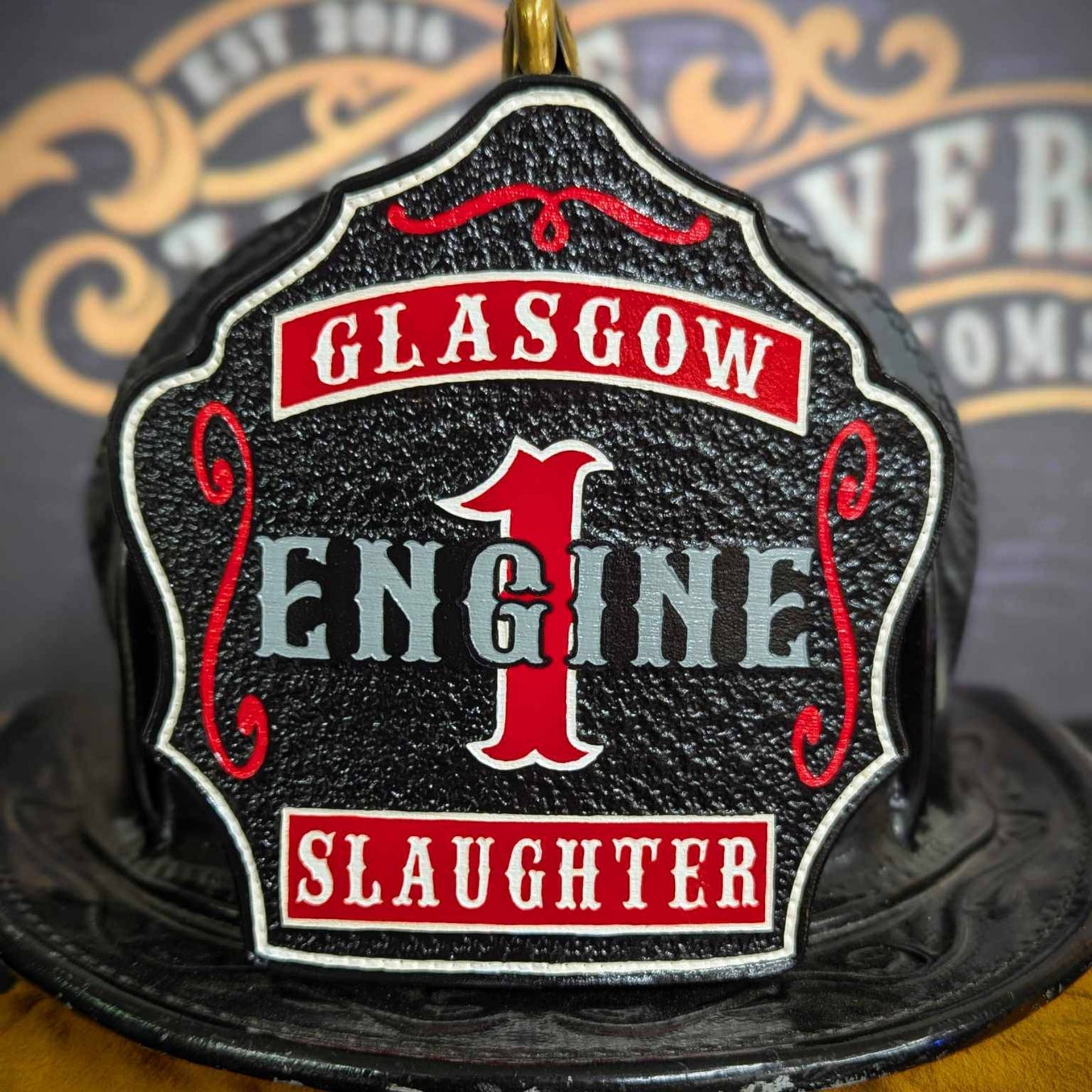 Black leather firefighter helmet shield with bold red number 1 and engine lettering, custom fire department gear.